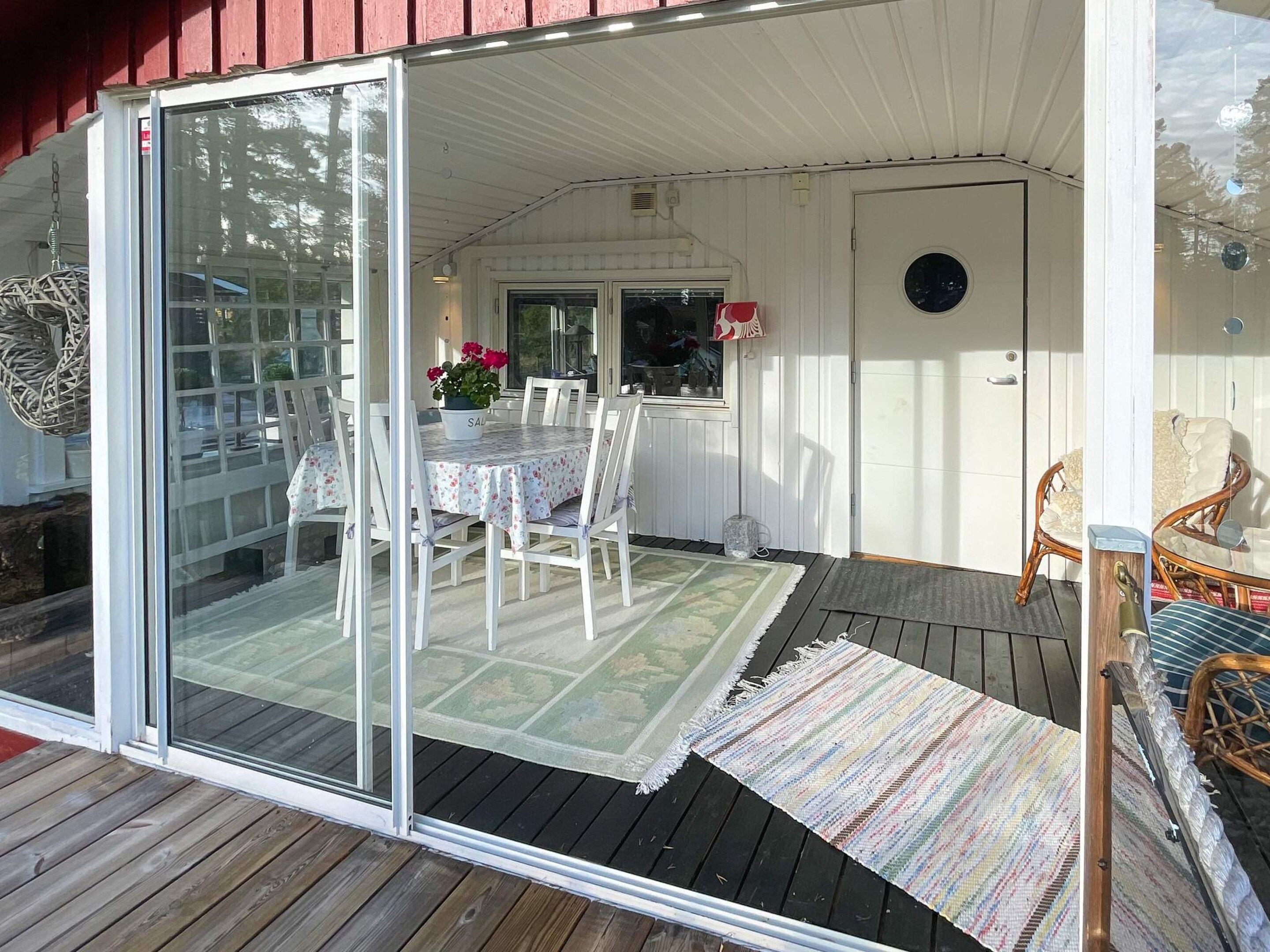 A covered patio with a table and chairs, a sliding glass door, and a small garden area with flowers.