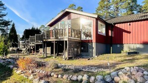 A modern house with a glass balcony, surrounded by a garden with rocks and plants. - 4 Person Holiday Home in Monsteras (Monsteras)