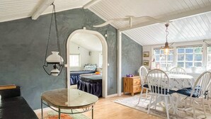 A cozy room with a bed, a dining table with chairs, a hanging light fixture, and a window with a view. - 4 Person Holiday Home in Monsteras (Monsteras)
