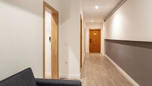 A hallway with a dark grey sofa, wooden door frames, and a wooden floor. - Albufera Dreams Nature Suites (Valencia)