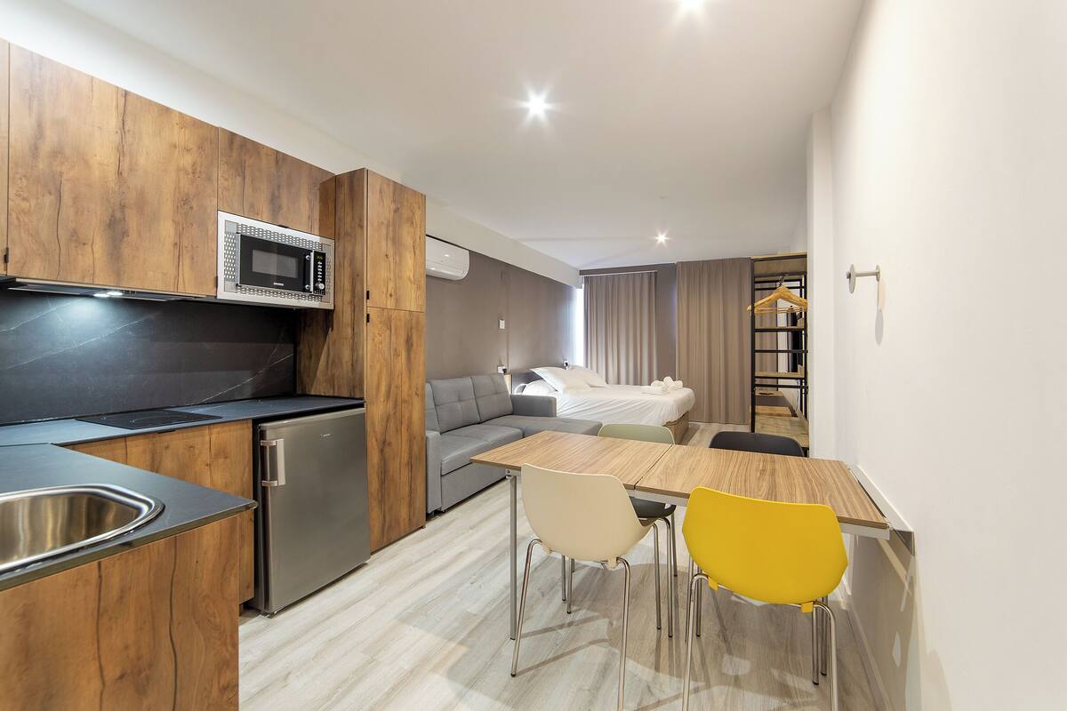 A modern kitchen with a microwave, refrigerator, and sink. There is a dining area with a table and chairs.