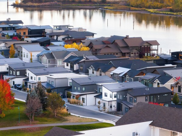 A residential area with modern houses, a lake, and a road.