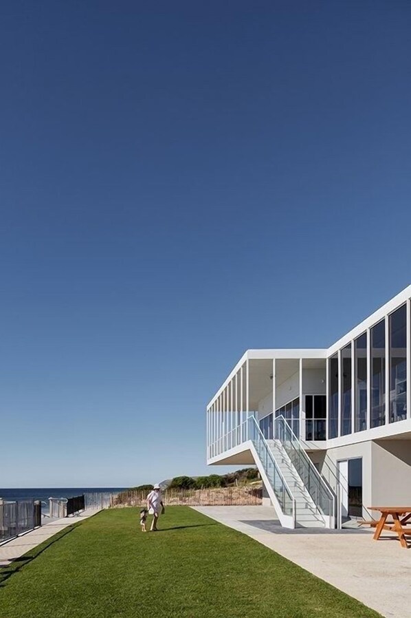A modern building with a glass facade, a grassy area, and a staircase leading to an upper level.