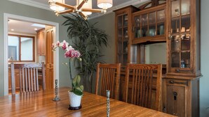 A dining area with a wooden table, chairs, a chandelier, and a cabinet with glass doors. - Luxurious Pacific Heights Retreat with Rooftop Deck (San Francisco)