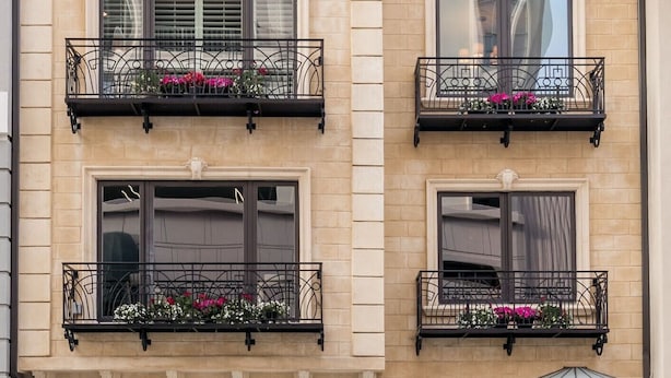A two-story building with a beige facade, black roof, and decorative iron balconies with flower boxes. - Luxurious Pacific Heights Retreat with Rooftop Deck (San Francisco)