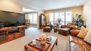 A spacious living room with a large flat-screen TV, leather sofas, a coffee table, and a bookshelf. - Luxurious Pacific Heights Retreat with Rooftop Deck (San Francisco)