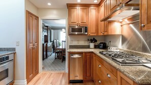 A modern kitchen with wooden cabinets, stainless steel appliances, granite countertops, and a dishwasher. - Luxurious Pacific Heights Retreat with Rooftop Deck (San Francisco)