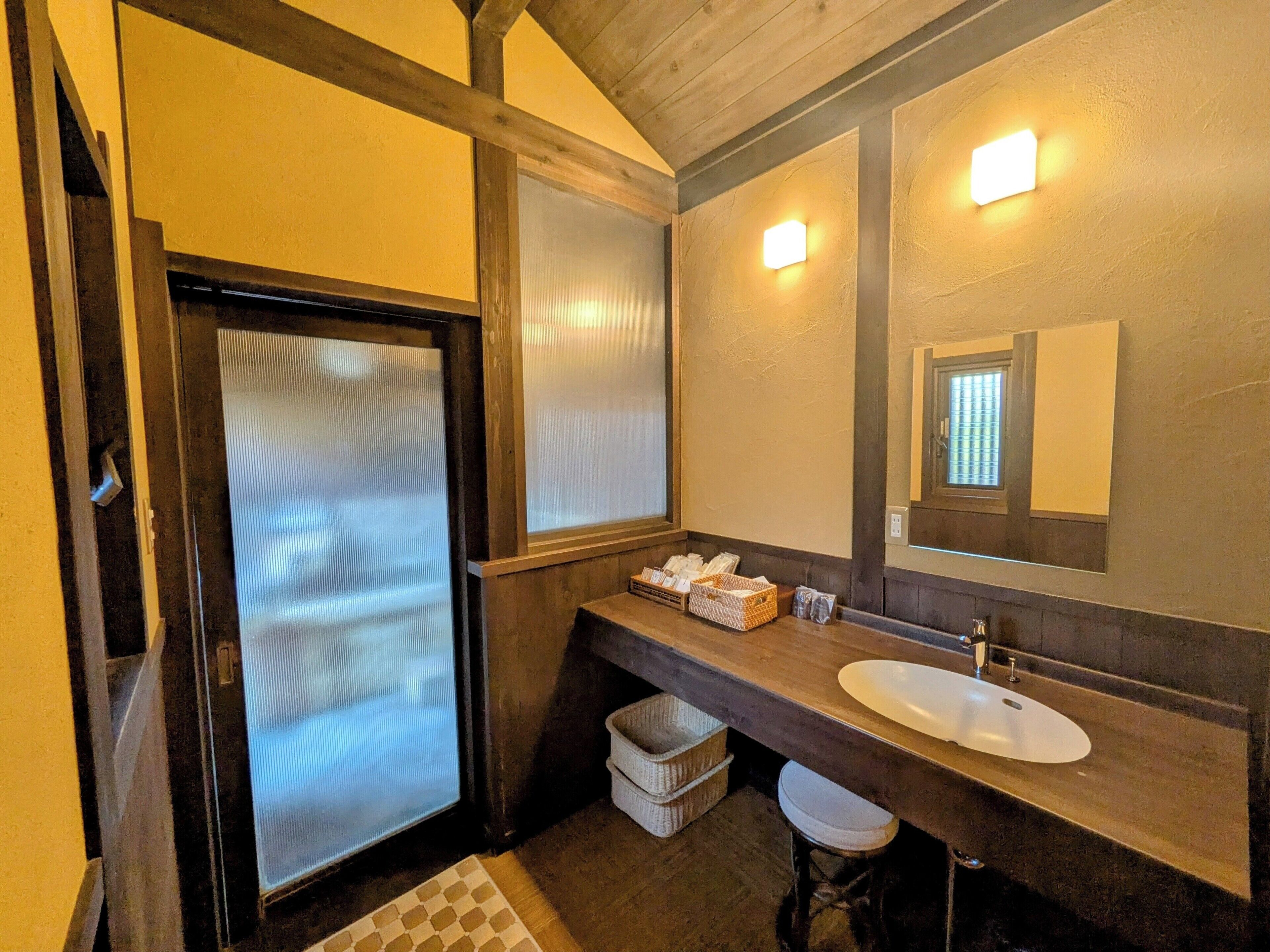 A bathroom with a wooden vanity, a large mirror, and a toilet.