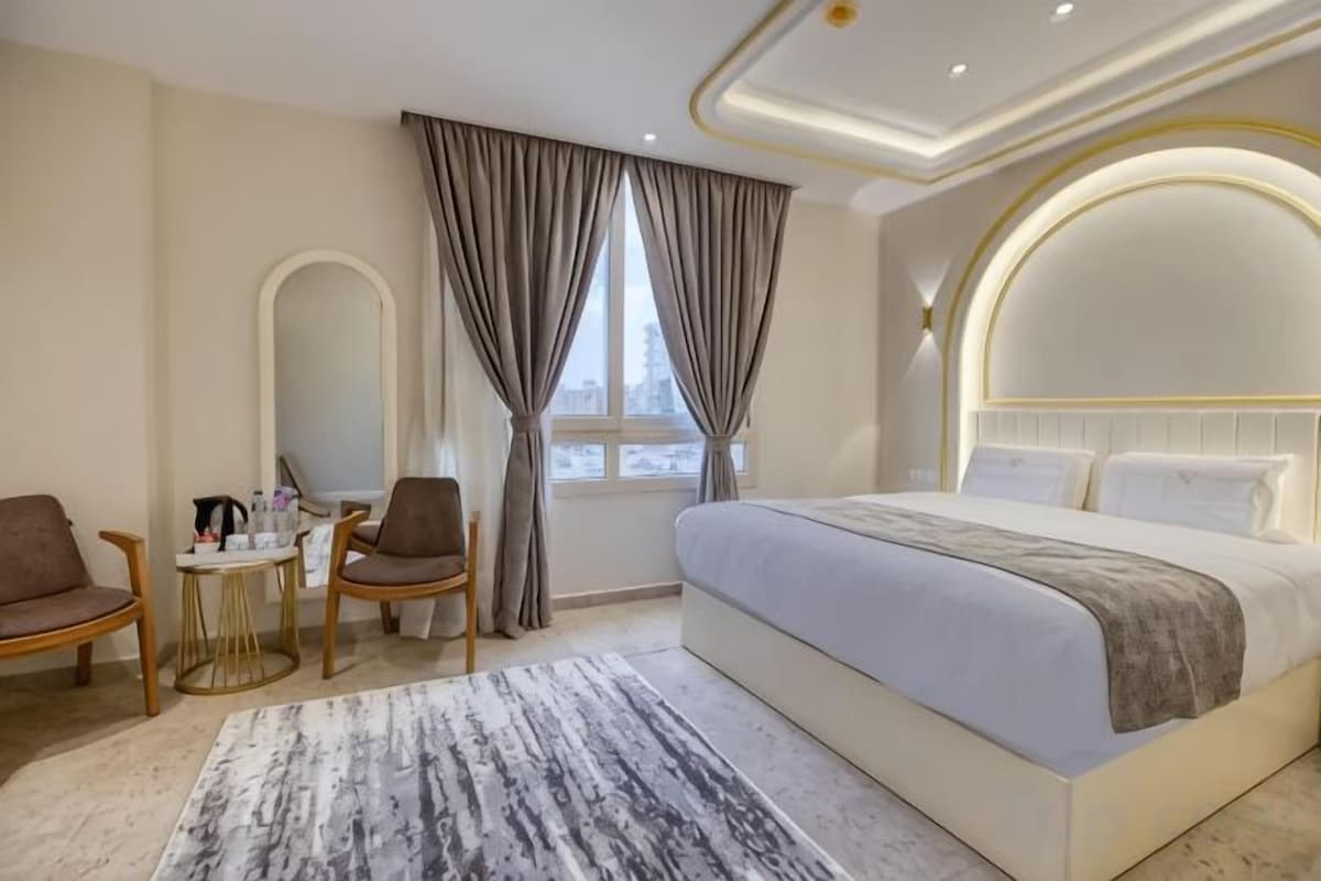 Habitación de hotel con una cama grande, un escritorio con silla, una ventana con cortinas y vistas al exterior.