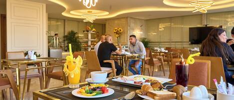 A dining area with tables, chairs, and a variety of food and drinks.