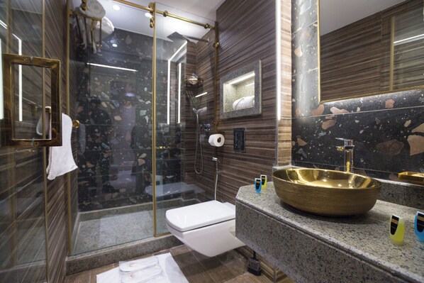 A modern bathroom with a glass-enclosed shower, a white toilet, and a large gold sink. - Pyramids Plateau Hotel (Giza)