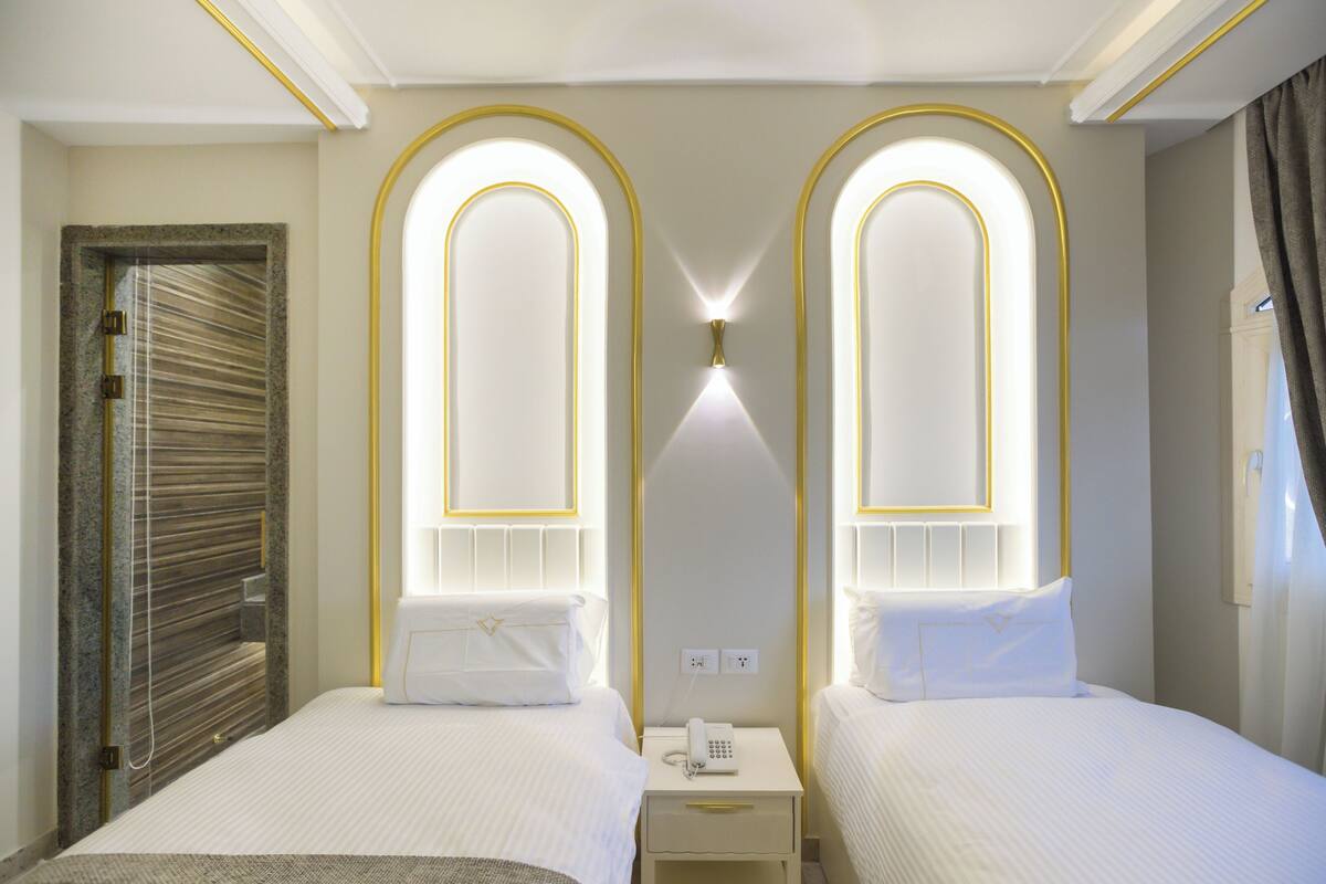 Ein Hotelzimmer mit zwei Betten, einem Nachttisch, einem Telefon und einer Wandleuchte.