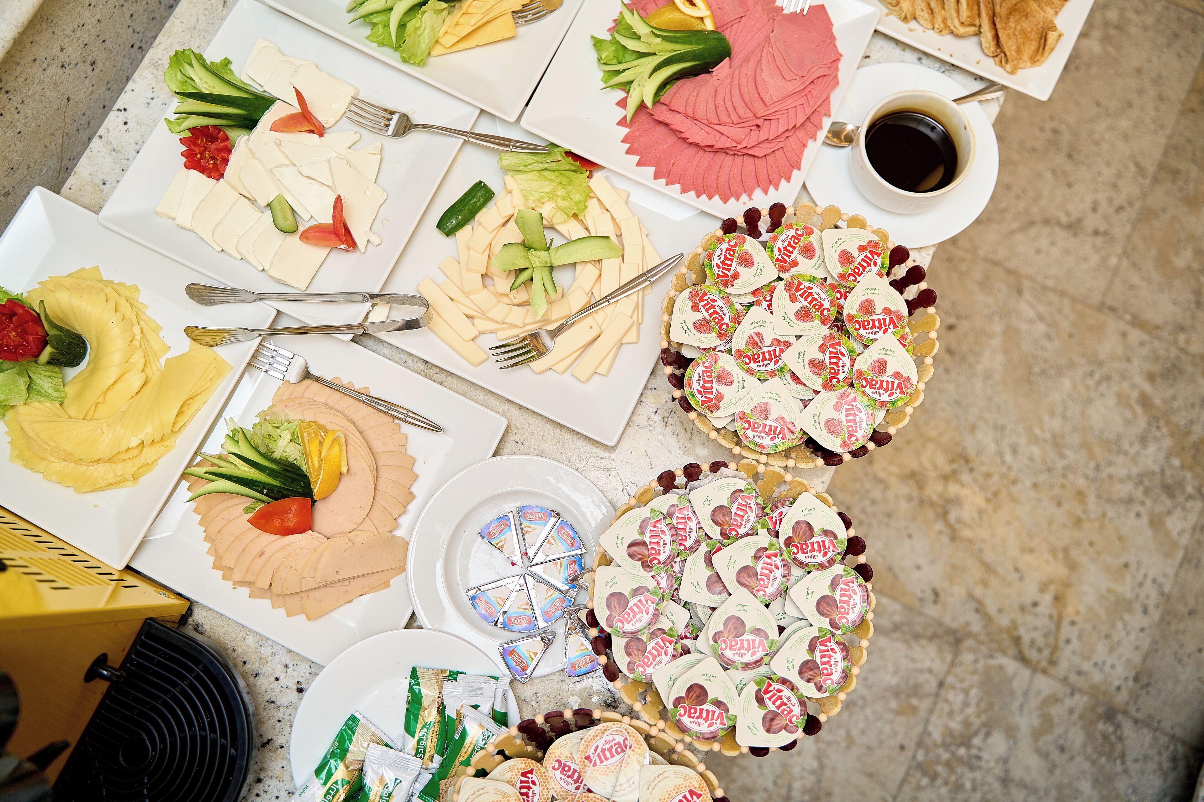 Une table garnie de divers aliments et condiments, notamment des charcuteries, des fromages, des fruits et des en-cas emballés.