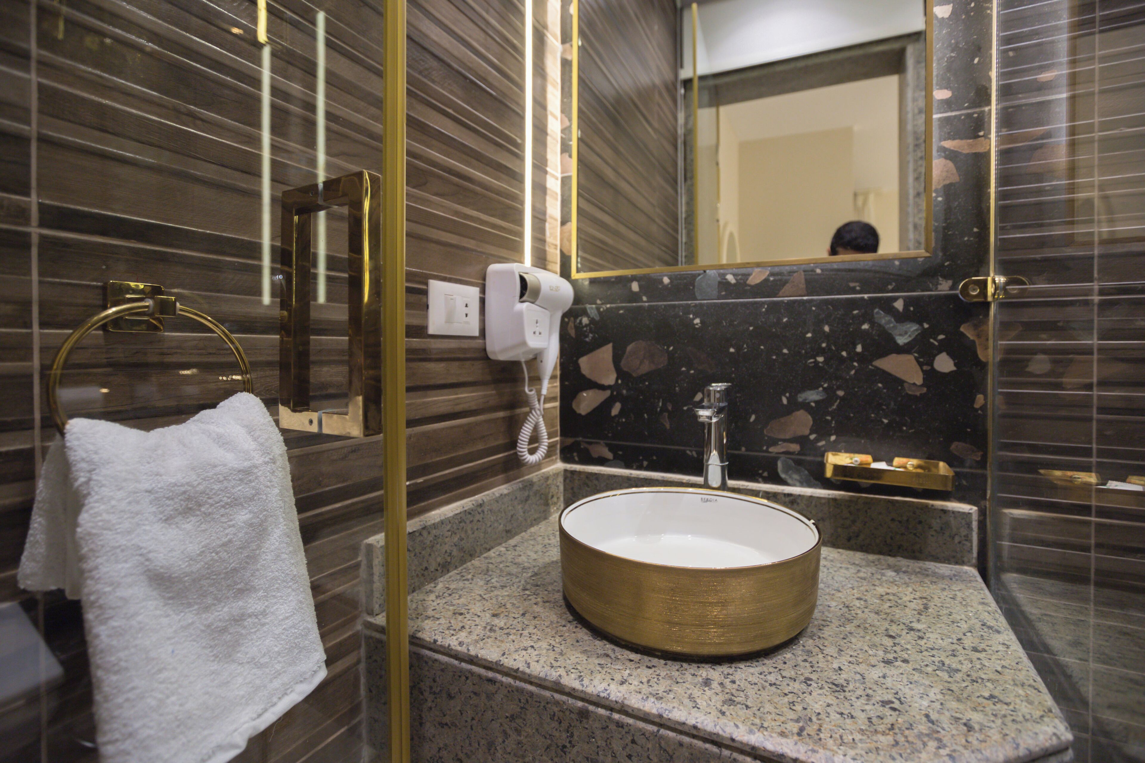 A bathroom with a round sink, a towel rack, a mirror, and a hand dryer.