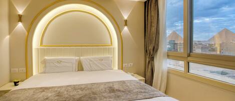 A hotel room with a large bed, a view of the pyramids, and a modern design.