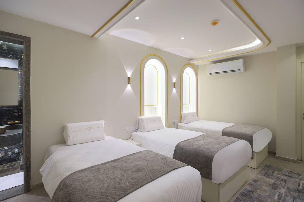 Ein Hotelzimmer mit zwei Betten, einem Badezimmer mit Marmorboden und einem modernen Deckenstil.