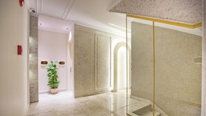 A hallway with marble flooring, a potted plant, and a glass partition with a golden frame. - Pyramids Plateau Hotel (Giza)