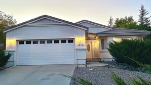 A two-story house with a white garage door, a small porch with a door, and a number '1712' on the garage door. - Spacious Pet-Friendly Home w/Fenced Yard & Central (Prescott)