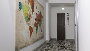 Um corredor com um grande mural de mapa-múndi, piso de ladrilho de pedra e uma porta com o número 301.