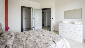 A bedroom with a bed, a dresser, a mirror, and a door leading to another room. - Agriturismo Liscio by Rentbeat (Noci)