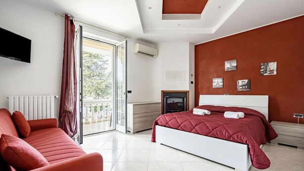 A bedroom with a bed, a sofa, a TV, and a balcony. - Agriturismo Liscio by Rentbeat (Noci)