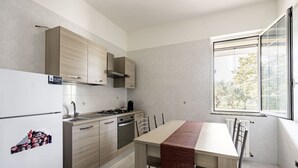 A modern kitchen with a dining table, cabinets, and a window. - Agriturismo Liscio by Rentbeat (Noci)
