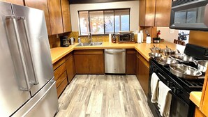 A compact kitchen with wooden cabinets, a stainless steel refrigerator, a dishwasher, a stove, and a microwave. - Spacious Sequoia Park 5 bed 3 bath house w/ AC & WIFI in charming Three Rivers (Three Rivers)