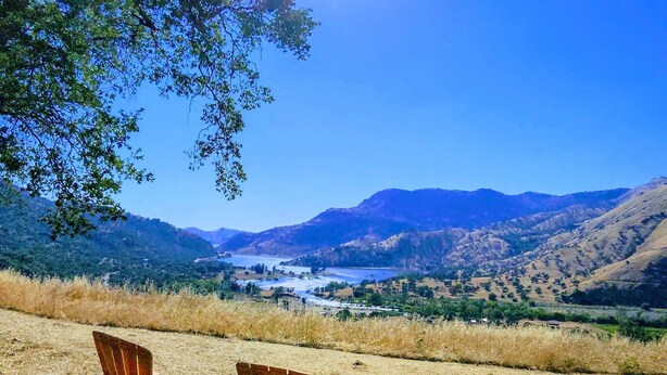 Three wooden Adirondack chairs facing a scenic landscape with mountains and a body of water under a clear blue sky. - Spacious Sequoia Park 5 bed 3 bath house w/ AC & WIFI in charming Three Rivers (Three Rivers)