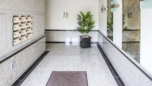A modern lobby with a granite floor, a potted plant, a security camera, and a wall-mounted intercom system. - Apartment With Spacious Terrace (Middelkerke)