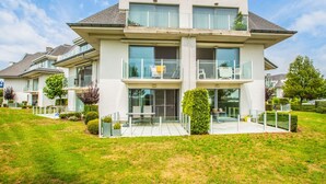 A modern two-story house with a balcony, large windows, and a well-maintained lawn. - Apartment With Spacious Terrace (Middelkerke)