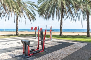 Outdoor exercise equipment, palm trees, and a beach view. - Estefânia Apartment by Atlantic Holiday (Santa Cruz)