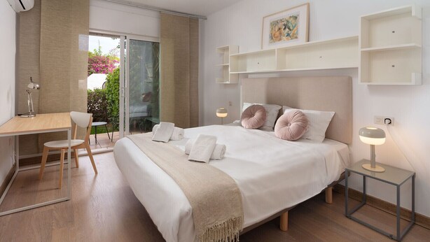 A modern bedroom with a large bed, bedside tables, a desk, and a chair.