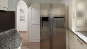 A stainless steel refrigerator in a kitchen with granite countertops and white cabinetry.