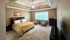 A bedroom with a bed, two armchairs, a TV, and a ceiling fan. - Spacious 5-bedroom house with AC, WiFi in charming Bluffton (Bluffton)