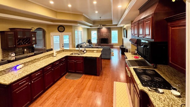 A spacious kitchen with granite countertops, dark wood cabinets, and a central island. - Spacious 5-bedroom house with AC, WiFi in charming Bluffton (Bluffton)