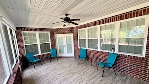 A covered patio with brick walls, large windows, and ceiling fans. - Spacious 5-bedroom house with AC, WiFi in charming Bluffton (Bluffton)