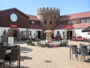 A courtyard with outdoor seating, a reception area, and a building with a stone tower. - 6 Person Holiday Park Home in Otterup (Otterup)