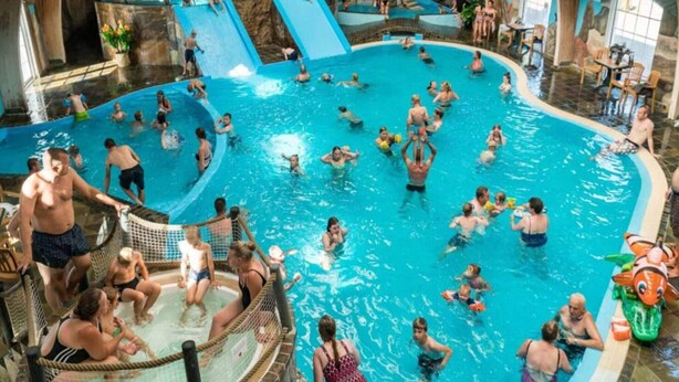 En inomhuspool med flera banor, rutschkanor och ett grunt område för lek.