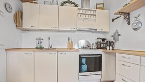 Una cucina con mobili bianchi, un fornello e una macchina da caffè.