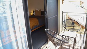 Una porta oberta que dona a un dormitori amb un llit, una cadira i una taula petita.