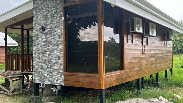 Een modern huis met een stenen gevel, grote ramen en buitenluidsprekers.