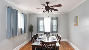 A dining room with a wooden table set for four, a ceiling fan, and a potted plant. - Serene modern 3-bedroom house in Shillington (Shillington)