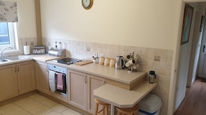A kitchen with a sink, stove, and a clock on the wall.