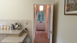 A kitchen with a countertop, a kettle, a coffee machine, and a door leading to a hallway.