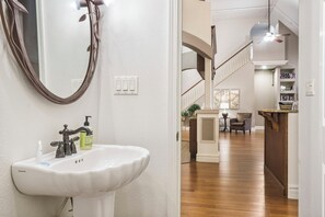 Un baño con lavamanos blanco, un espejo y dispensador de jabón.