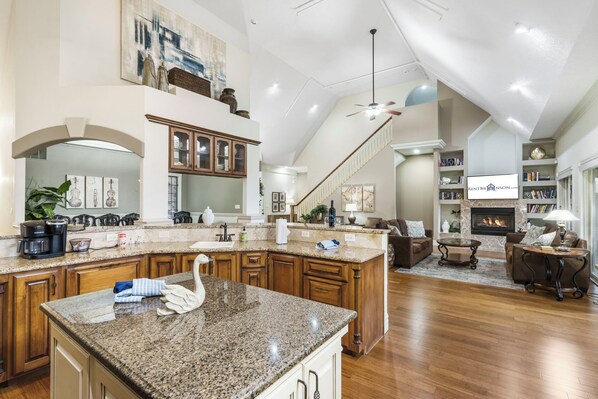 A spacious kitchen with granite countertops, wooden cabinets, and a decorative swan centerpiece.
