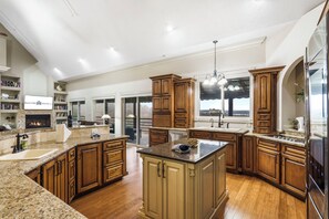 A spacious kitchen with granite countertops, wooden cabinets, and a large island.