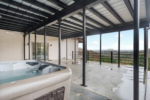 Un espace extérieur abrité, doté d’un jacuzzi, de poutres métalliques et offrant une vue sur un paysage lointain.
