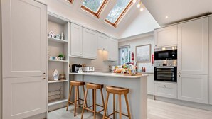 A modern kitchen with a central island, bar stools, and built-in appliances.