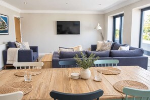 Un salon moderne avec deux canapés, une table basse et un téléviseur fixé au mur.